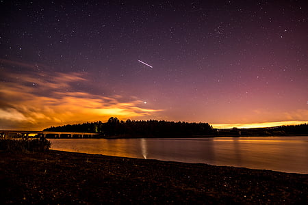 body of water under gray and yellow sky during nighttime thumbnail