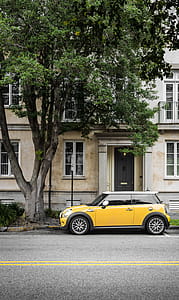 Yellow Mini Cooper Parked Beside White Concrete Building thumbnail