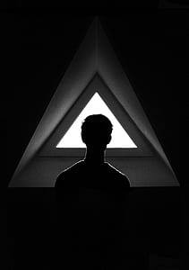 grayscale photo of man looking at triangle window thumbnail