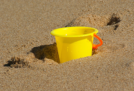 yellow plastic cup in brown sand thumbnail