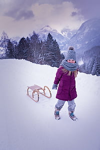 woman wearing pink jacket pulling sled on snowfield thumbnail