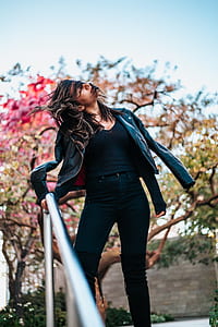 selective focus photography of woman in black leather jacket standing beside handrail thumbnail