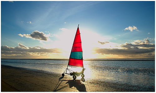 red and blue sailboat on beach under blue sky thumbnail