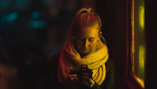 woman holding DSLR camera near window thumbnail