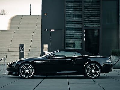 black soft-top coupe on parking area near building at daytime thumbnail