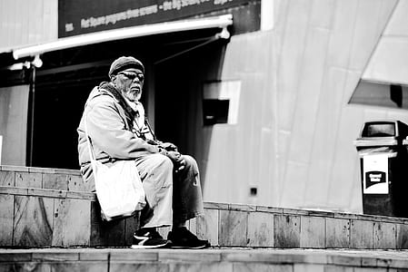 grayscale photography of man sitting on wood planks thumbnail