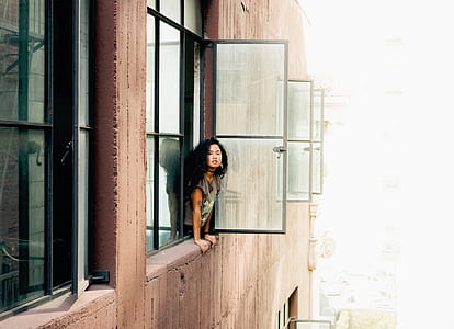 woman leaning on window during daytime thumbnail