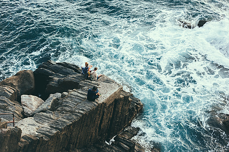 two men and woman on rock cliff beside a sea thumbnail