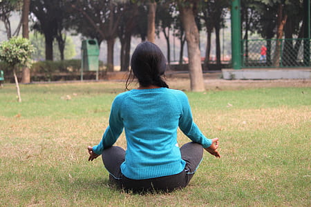 meditating woman on grass during daytime thumbnail