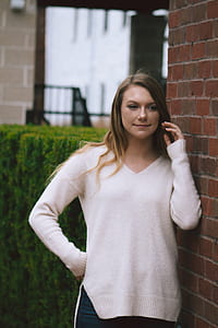 shallow focus photography of woman leaning on wall during daytime thumbnail
