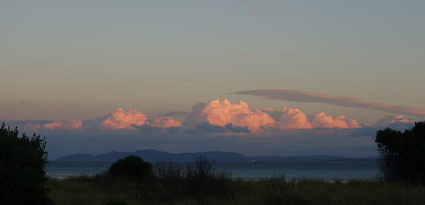 Sunset reflection of pink clouds over blue mountains thumbnail