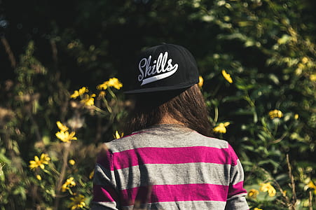 Woman in Gray and Pink Longsleeve Shirt Wearing Black Skill Printed Cap thumbnail