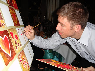 man painting brown and red hearts on white canvas thumbnail
