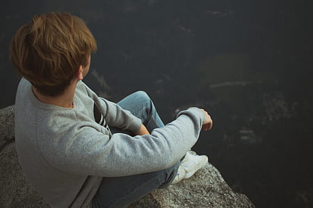 man sitting on rock cliff thumbnail