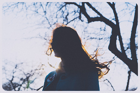 silhouette of woman smiling under bare tree thumbnail