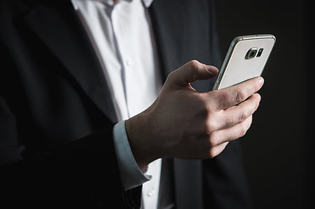 person in black formal coat holding Samsung Galaxy Android smarpthone thumbnail
