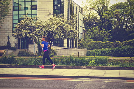 woman running along the street near building during daytime thumbnail