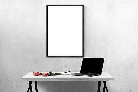 black laptop computer turned-off on white wooden table near black wooden photo frame thumbnail