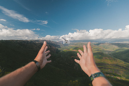 quadcopter drone in front of person and mountains in background thumbnail