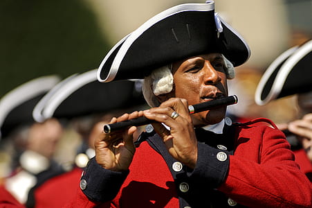 Man in Red and White Musical Suit Playing Flute during Daytime in Camera Focus Photography thumbnail