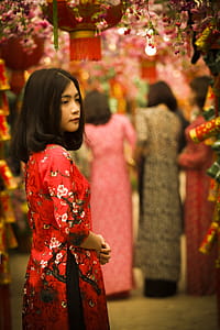 Woman in Red and White Floral Slit Dress Standing in Red Floral Arch thumbnail