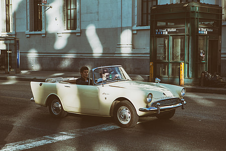 Two people sit in an open-top classic car (Sunbeam Alpine) on the streets of Manhattan, New York City thumbnail
