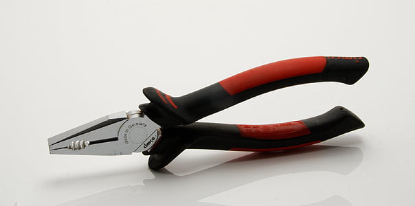 stainless steel pliers with red and black handle on white floor thumbnail
