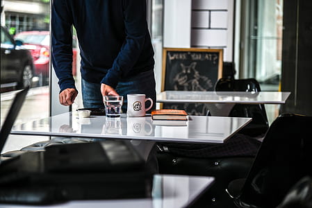 person standing beside glass table with mug thumbnail