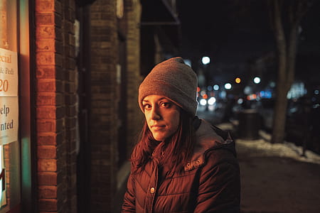 woman in black bubble jacket wearing grey beanie standing in front of establishment thumbnail