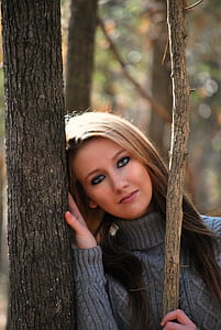 Woman in Grey Sweater Lying on Tree during Daytime thumbnail