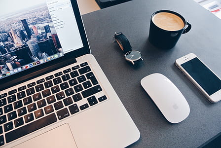 MacBook pro near Apple Magic Keyboard, silver iPhone 5s, and black ceramic mug thumbnail