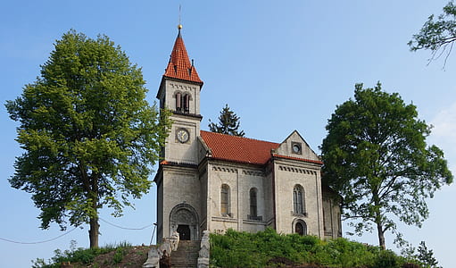architectural photography of cathedral on top of grass-covered rock formation thumbnail