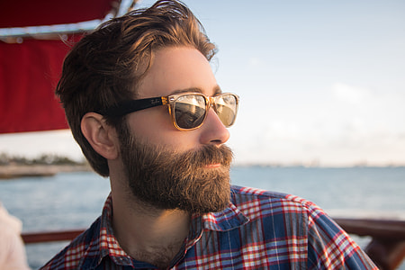 man in blue, red and white plaid shirt looking on sea during sunset shallow focus photography thumbnail