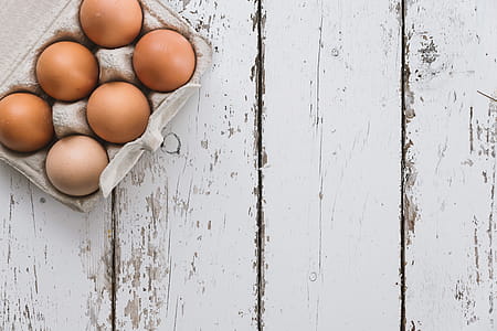Close-up view of chicken eggs in egg box on white wooden background thumbnail