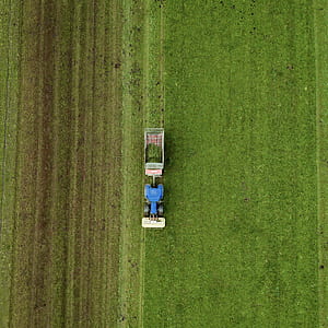 blue and white farm tractor plowing field thumbnail