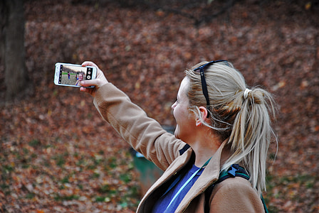 photo of a woman wearing brown jacket holding white Android smartphone thumbnail