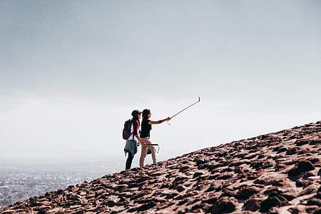 Two young Caucasian female hikers wearing sunglasses taking selfie on a cobblestone hill thumbnail