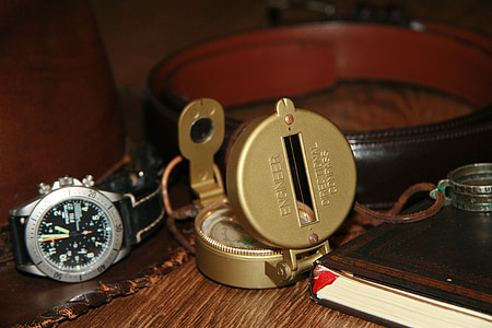 black chronograph watch beside gold compass thumbnail