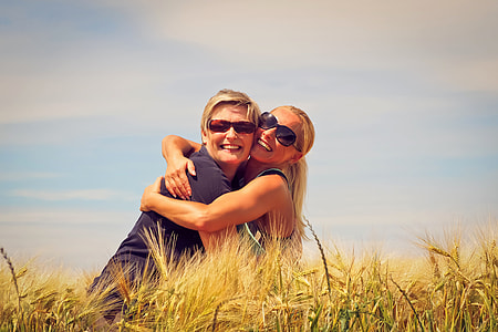 two women hugging beside brown grasses during daytime thumbnail