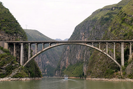 gray concrete bridge near over river near mountains thumbnail