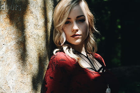 woman wearing red scoop-neck shirt standing near brown concrete wall at daytime thumbnail