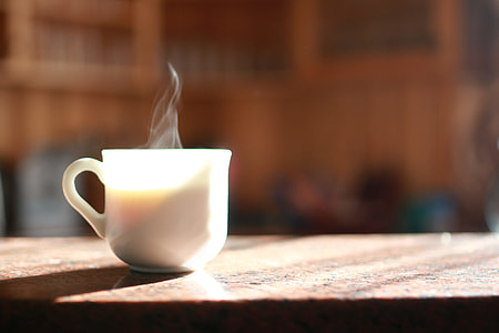 shallow focus photography of white ceramic mug on brown wooden table during daytime thumbnail