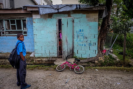 boy standing in front of blue concrete house thumbnail