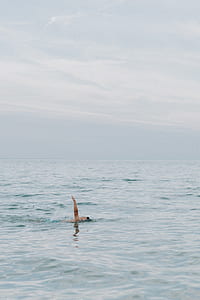 person swimming on body of water thumbnail