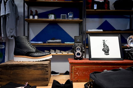 black full-brogue boots on wooden box in front of box with photo frame on top in room thumbnail