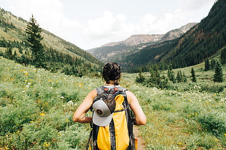 woman wearing yellow and black backpack walking on green field thumbnail