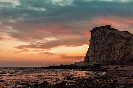 rock formation near body of water during dawn thumbnail