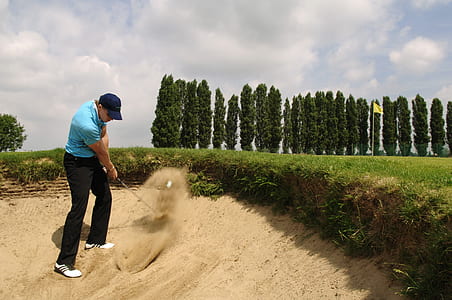 man wearing teal shirt and black pant playing golf thumbnail