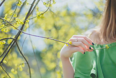 Closeup Photography of Woman Wearing Green Top Holding Leaf thumbnail