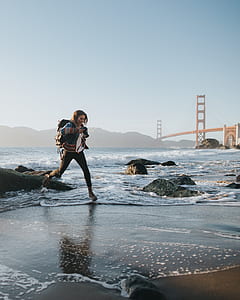 woman walking beside body of water during daytime thumbnail